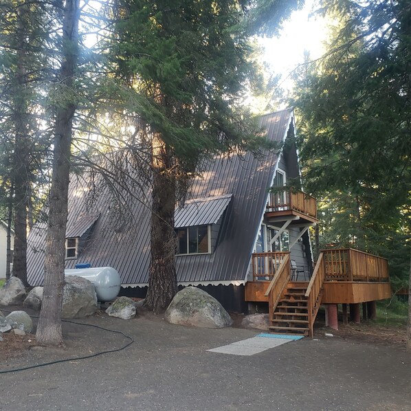 A cabin with a steeply pitched roof, wooden deck, and a staircase leading to an upper level. - Charming 2-bedroom A Frame modern cabin in McCall perfect for a cozy getaway (McCall)
