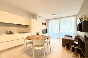 Ein modernes Wohnzimmer mit einem runden Holztisch, weißen Stühlen, einer Couch und einem Fernseher.