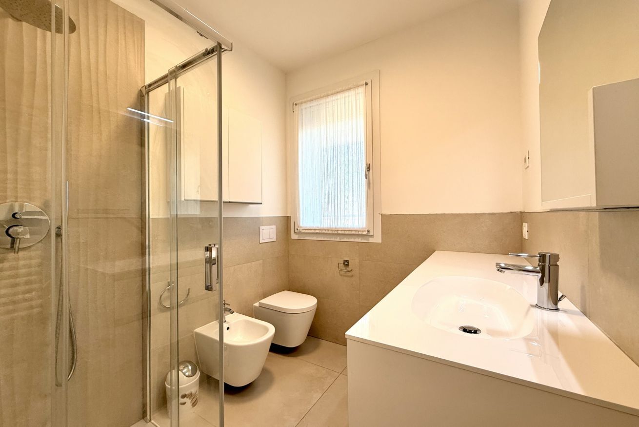A modern bathroom with a glass shower enclosure, a white sink, and a toilet.