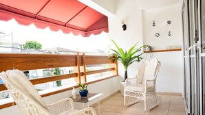 En balkon med to fletstole, et lille bord og en potteplante.