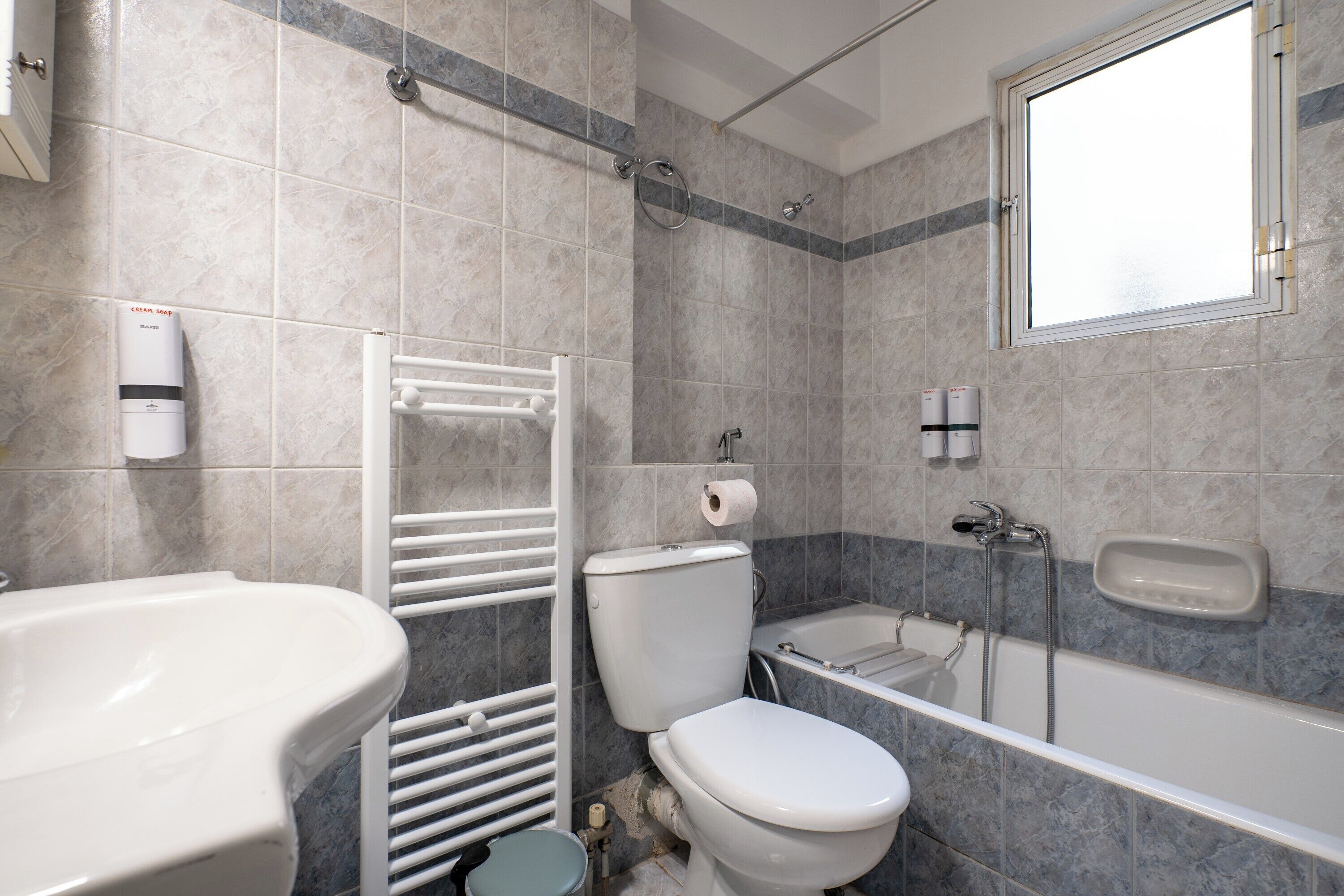 Une salle de bain comprenant des toilettes, un lavabo, une baignoire et une fenêtre.
