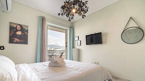 Una camera d'albergo con un letto, una TV a schermo piatto, un quadro della Gioconda e vista attraverso la porta.