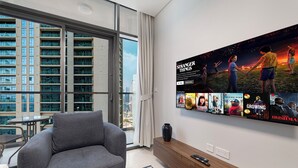 Un soggiorno moderno con un divano grigio, un tavolino da caffè e una parete con la TV e poster di film.