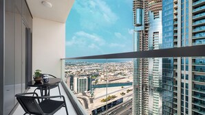 Un balcone con tavolo e sedie, affaccia su un paesaggio urbano con grattacieli e un fiume.
