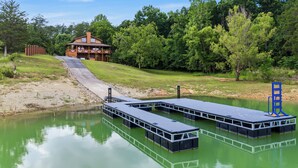 Uma cabana à beira do lago com um píer, um deck coberto e um edifício com chaminé.