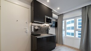 Cozinha moderna com bancada preta, eletrodomésticos de aço inoxidável e janela com vista para edifícios.