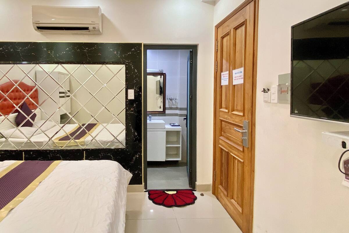 A hotel room with a bed, a bathroom, and a TV.