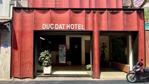 L'esterno dell'Hotel Duc Dat, con una facciata rossa ben visibile e un frigorifero Coca-Cola all'esterno.