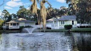 A lakeside property with two houses, a dock, and a fountain. - 2 bedroom 2 bath condo with deck overlooking lagoon. (Saint Simons Island)