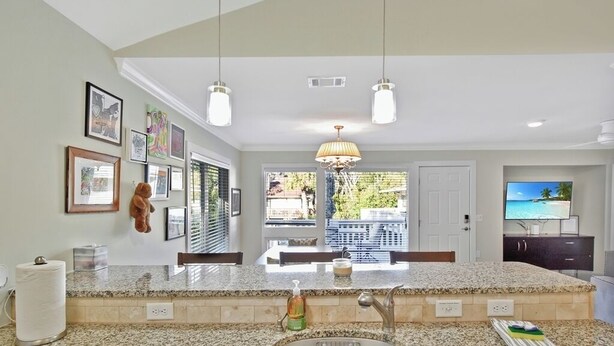 A kitchen with granite countertops, a stainless steel sink, hanging pendant lights, and a view of the outdoors through the window. - 2 bedroom 2 bath condo with deck overlooking lagoon. (Saint Simons Island)