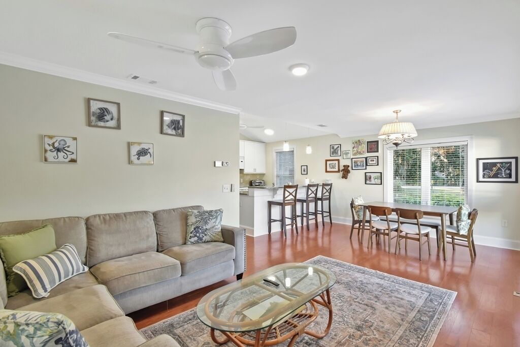 A living room with a sofa, coffee table, and dining area with chairs.