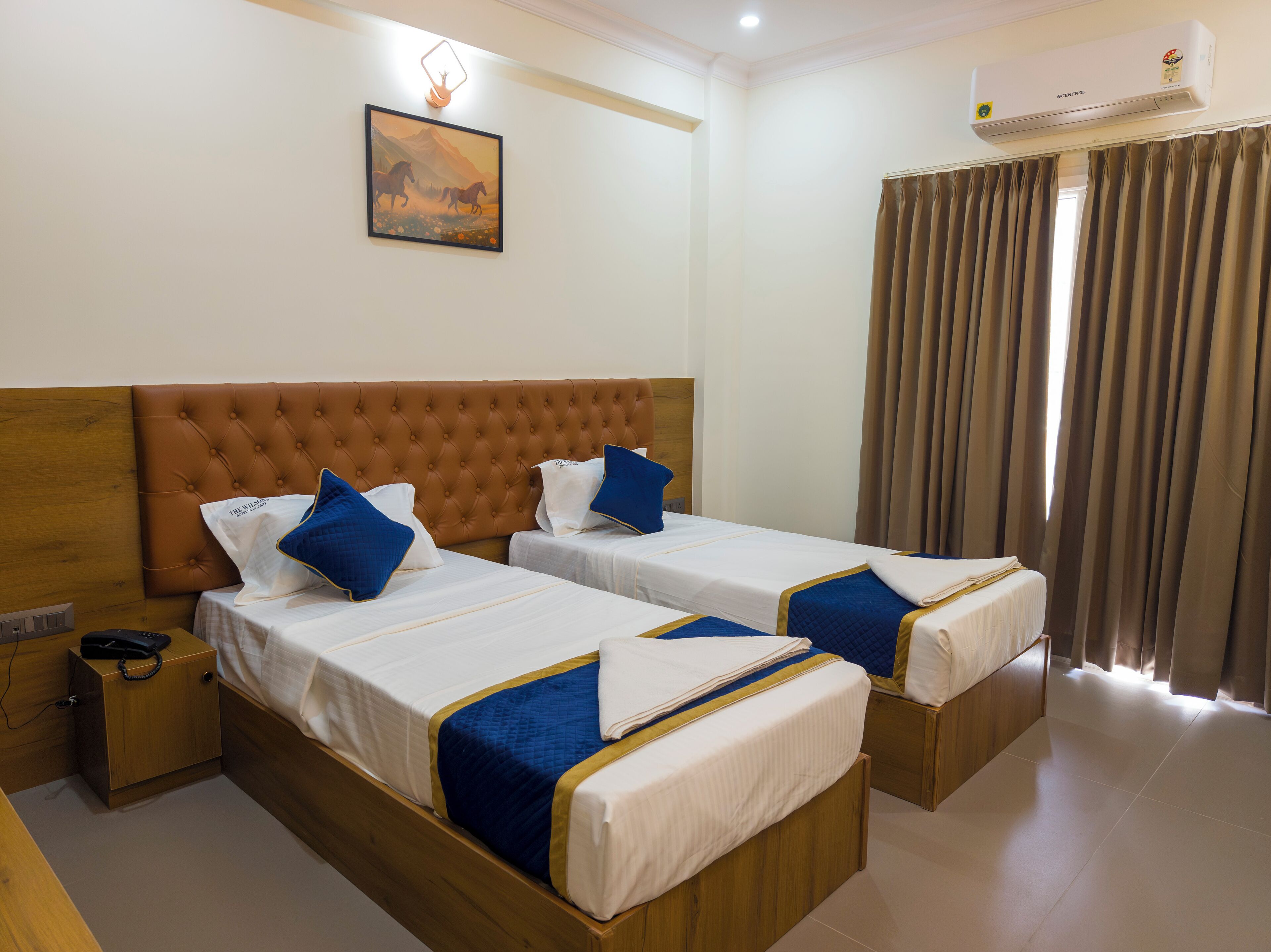 A hotel room with two beds, a wooden headboard, a painting on the wall, and an air conditioning unit.
