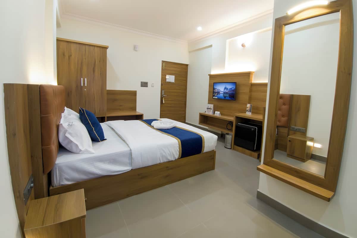 Una moderna camera d'hotel con un letto di legno, una scrivania con un computer, una televisione e uno specchio grande.