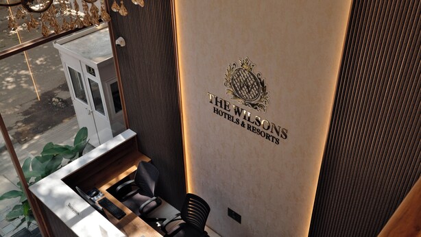 Un taulell de recepció amb disseny modern, un logotip de The Wilsons Hotels & Resorts i vista del carrer.