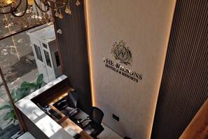 Un comptoir d’accueil au design moderne, le logo de la chaîne The Wilsons Hotels & Resorts, et une vue sur la rue.