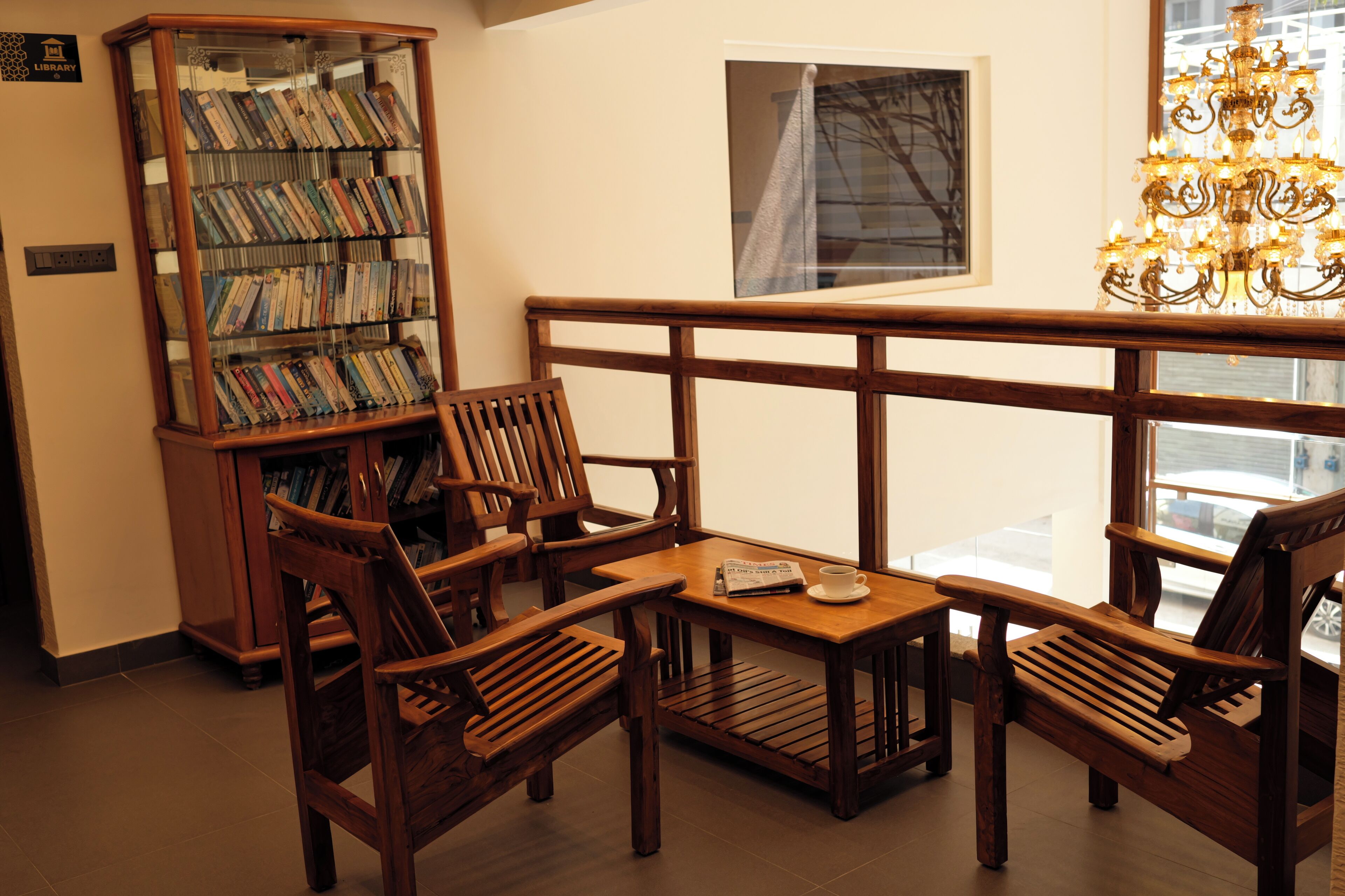 A library with wooden bookshelves, a reading bench, and a chandelier.