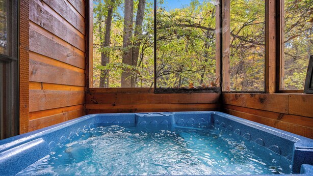 Un jacuzzi con vistas a un bosque a través de una ventana.