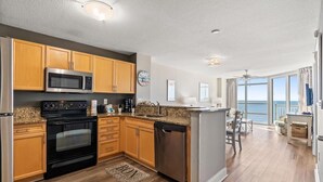 A modern kitchen with wooden cabinets, a microwave, stove, and dishwasher. - Cozy 2-bedroom condo with AC in peaceful North Myrtle Beach with amazing view (North Myrtle Beach)