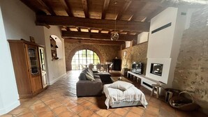 Un espacio habitable amplio con chimenea, techo de madera y un gran ventanal arqueado.
