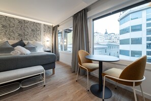 Ein modernes Hotelzimmer mit einem Bett, einer Couch, einem runden Tisch und Stühlen.