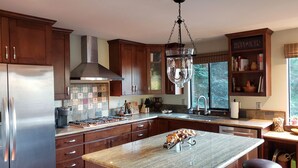 Une cuisine moderne dotée d’un îlot central, d’appareils électroménagers en acier inoxydable et de meubles de rangement en bois.