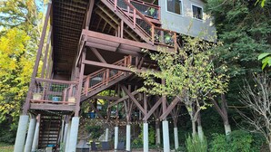 Une structure en bois à plusieurs niveaux, dotée d’un espace extérieur aménagé pour s’asseoir et illuminée de guirlandes lumineuses.