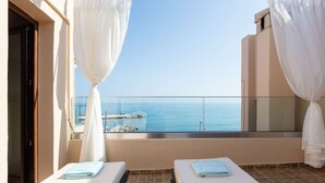 Ein Balkon mit zwei Betten und Meerblick, im Hintergrund ein Gebäude.