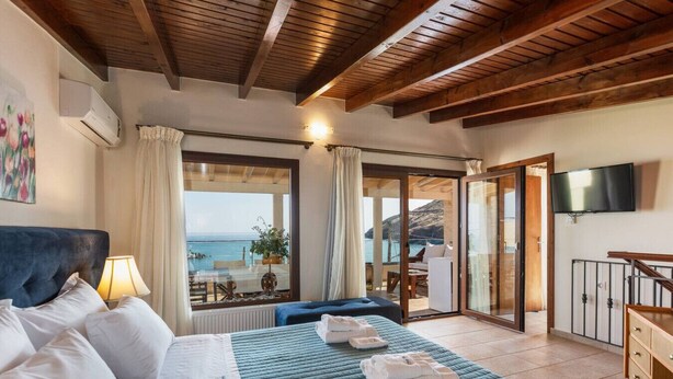 Ein Schlafzimmer mit Bett, Nachttisch, Fernseher und Meerblick.