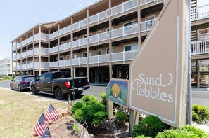 A multi-story hotel with balconies, a sign reading "Sand Pebbles," and American flags in the foreground. - 2-Bed 2-Bath Oceanfront Condo in Carolina Beach with 2 Pools and Beach Access! (Carolina Beach)