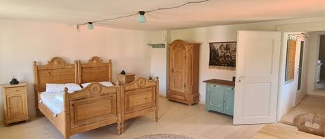 A bedroom with a wooden bed, a wardrobe, a cabinet, and a painting on the wall.