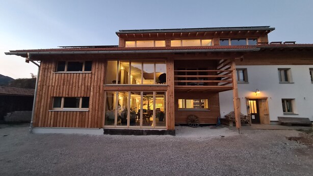 Ein zweistöckiges Holzhaus mit großen Fenstern und einem Balkon.