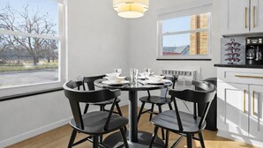 Een moderne keuken met een ronde eettafel, zwarte stoelen en een hanglamp.