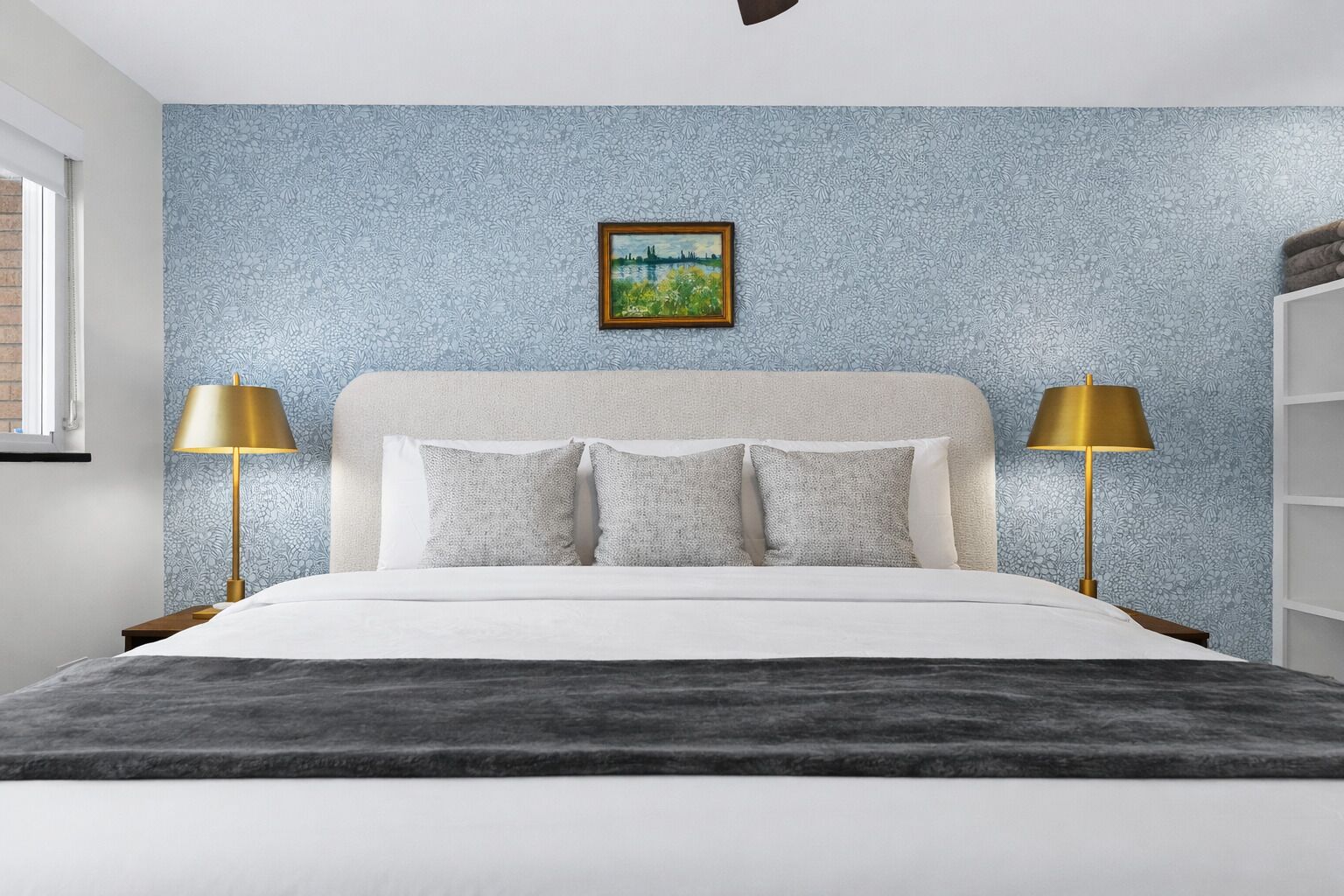 Un dormitorio con una cama, dos lámparas de noche, un cuadro en la pared y una ventana.