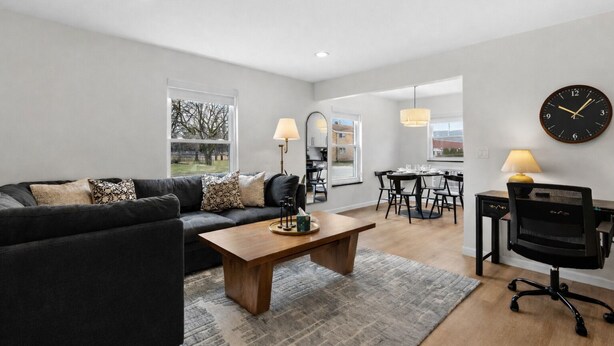 Een moderne woonkamer met een bank, salontafel en een eethoek met stoelen en een tafel.