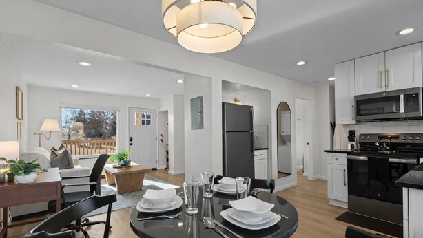 A modern kitchen with a dining area, featuring a round table set for four, a refrigerator, a microwave, and an oven. - Charming 1BR Getaway | Eastpointe (Eastpointe)