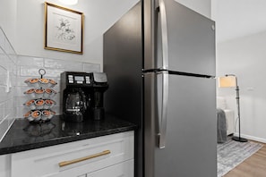 A kitchen with a stainless steel refrigerator, a coffee maker, and a framed picture on the wall. - Bright & Airy 1BR w/ Workspace + Laundry | WiFi, in Eastpointe (Eastpointe)