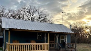 A small house with a porch and a metal roof. - Cozy 1-bedroom cabin in lovely Rising Star with AC (Rising Star)