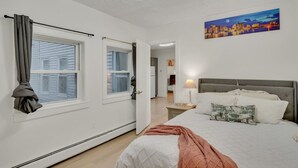Una camera da letto con un letto, un comodino, una lampada, un quadro e vista sulla città.