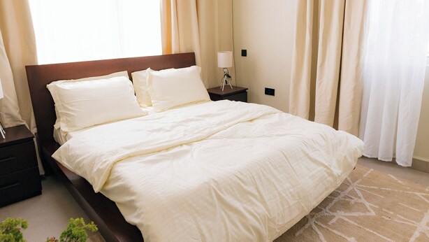 A neatly made bed with white linens in a hotel room. - Modern, Spacious Apartment — Your Home Away From Home (Dar es Salaam)
