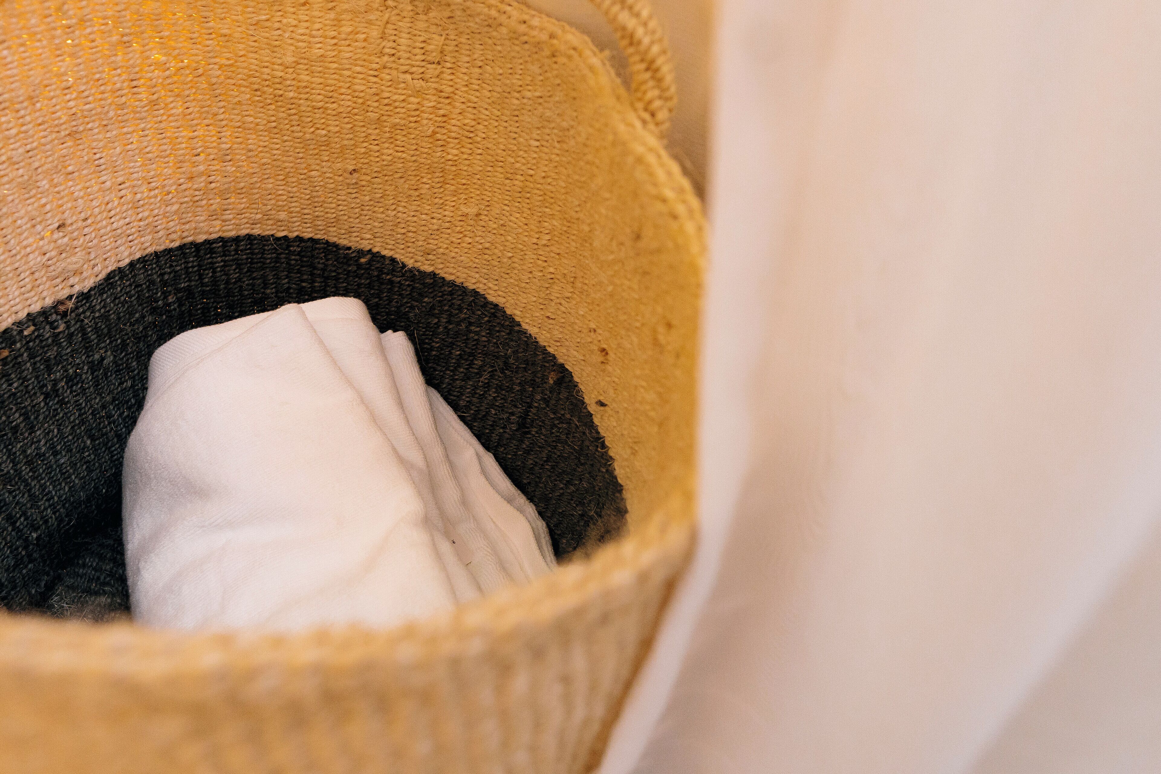 A close-up of a woven basket with a folded white cloth inside.
