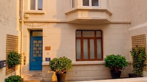 A two-story building with a blue door, a large window with a wooden frame, and potted plants in front. - L'Écrin d'Opale: Historic Suite 60m² • King Size Bed • Old Town (Boulogne-sur-Mer)
