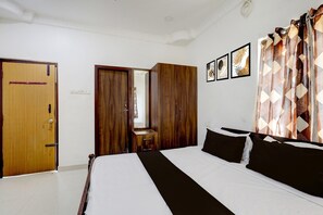 A bedroom with a bed, wooden wardrobe, a small table, and a mirror. - Hotel O Oragadam Industrial Estates Chennai (Sriperumbudur)
