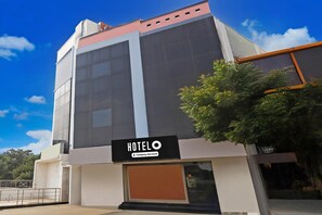 A modern hotel building with a prominent 'HOTEL O' sign, large windows, and a visible entrance.