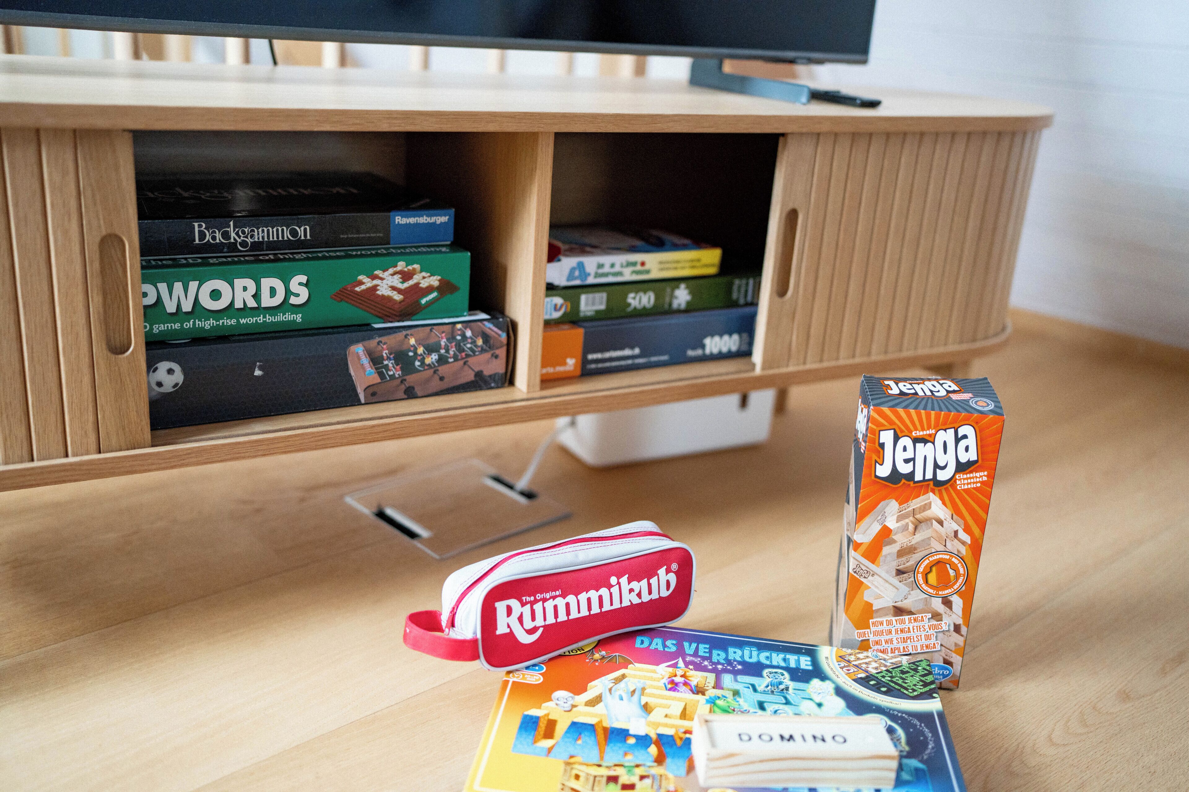 A wooden entertainment unit with board games and a television.