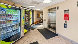 Un distributeur automatique proposant une variété de boissons et d’en-cas, un ascenseur muni d’un panneau de sécurité et un sol carrelé.
