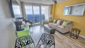 Un salon moderne avec balcon, un coin repas et un ensemble de canapés.