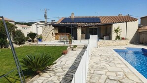 Ein Wohnhaus mit Swimmingpool, Außenbereich und einer Steinterrasse.