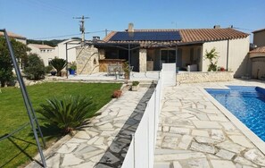 A residential property with a swimming pool, outdoor seating, and a stone patio. - Air-conditioned house with garden and private pool near Avignon and Pont du Gard (Tavel)