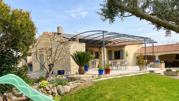 Ein Haus mit überdachter Terrasse, einem Rasen und einer Rutsche.