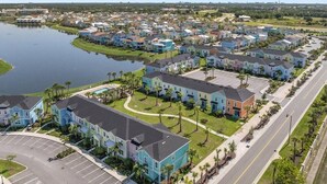 A residential area with houses arranged in rows along a road, a body of water to the left, and a parking lot in the foreground. - Cozy villa in Margaritaville Orlando, near Disney, SeaWorld, Universal (Kissimmee)